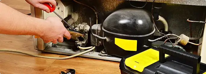 Refrigerator repair technician fixing the compressor and wiring in Camp H M Smith, HI