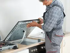 Appliance repair technician installing a built-in cooktop in Honolulu, HI