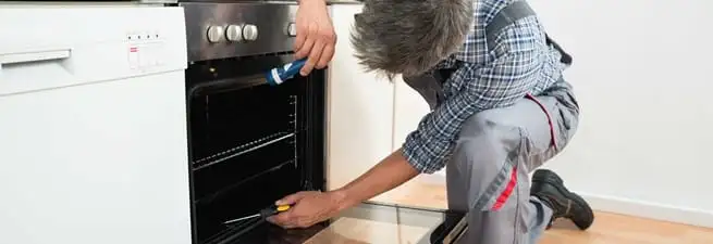 Oven repair technician inspecting and servicing an electric oven in Honolulu, HI