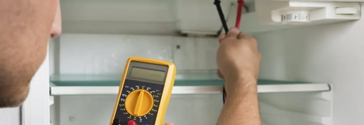 Refrigerator repair technician testing electrical components with a multimeter in Honolulu, HI