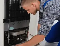 Refrigerator repair technician servicing the compressor and condenser area in Honolulu, HI